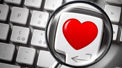 Rote Herzform auf einer Computertastatur, vergrößert durch eine Lupe.