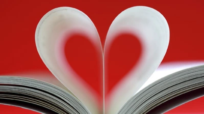 Aufgeschlagenes Buch mit zwei nach innen gebogenen Seiten, die ein Herz formen.